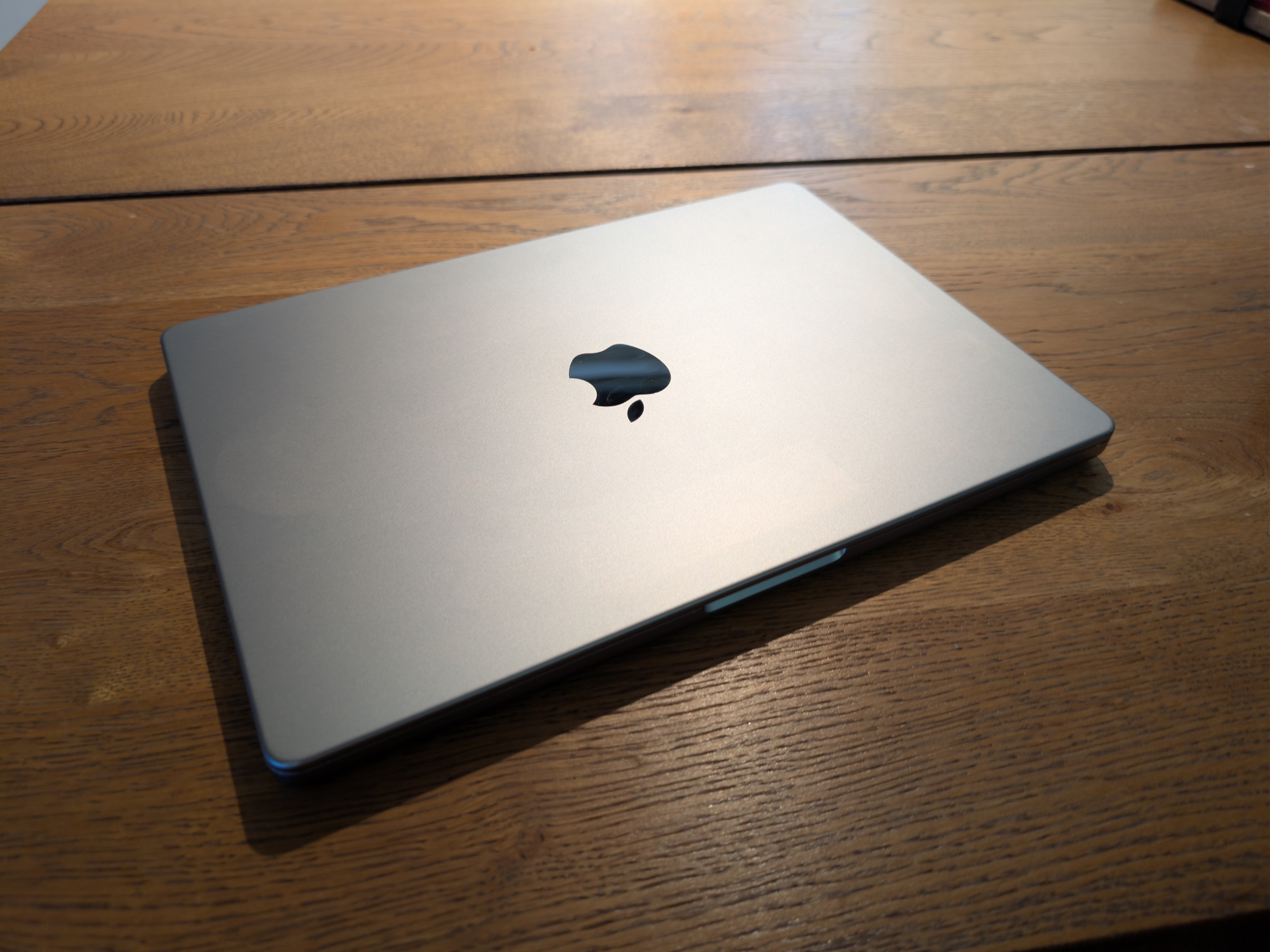 The closed 14-inch MacBook Pro used for the local AI test, photographed on a wooden table.