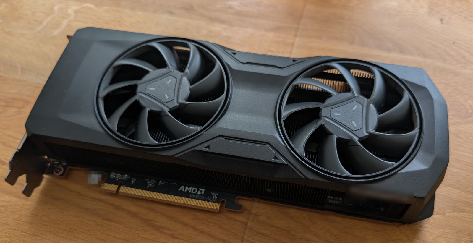 The RX 7800 XT seen from its PCB edge, showing the PCIe connector and the AMD board silkscreen.